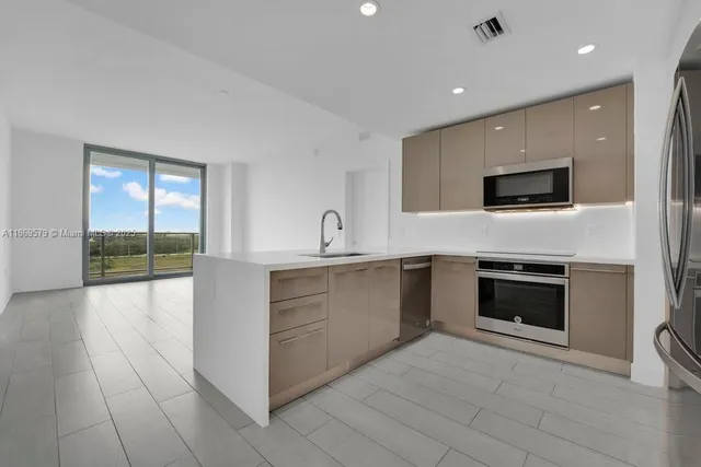 a large white kitchen with granite countertop a sink and a stove top oven