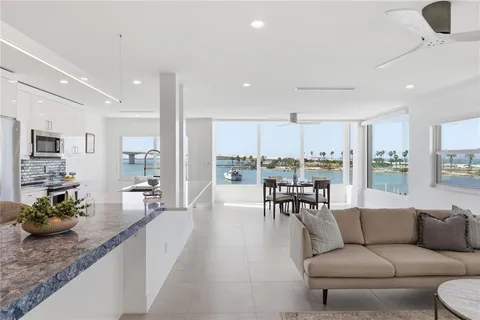 a living room with furniture wooden floor kitchen view and a large window