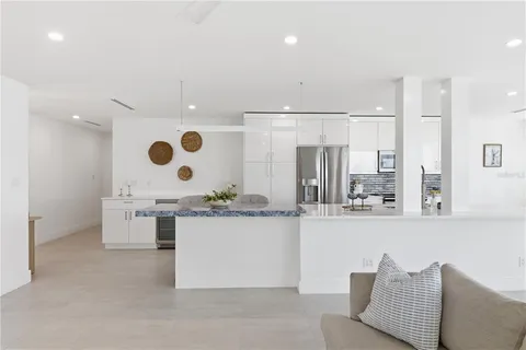 a large white kitchen with stainless steel appliances kitchen island granite countertop a sink and cabinets