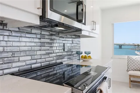 a living room with couches a chandelier and kitchen view