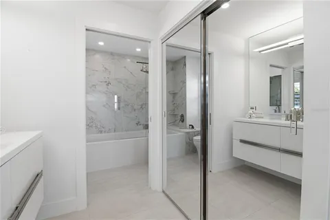 a bathroom with a double vanity sink and mirror with bathtub