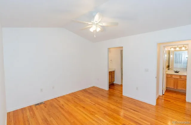 a view of a room with wooden floor and a ceiling fan