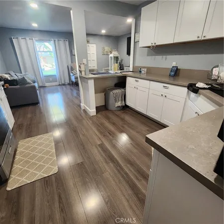 a kitchen with a sink dishwasher a stove a dining table and chairs with wooden floor