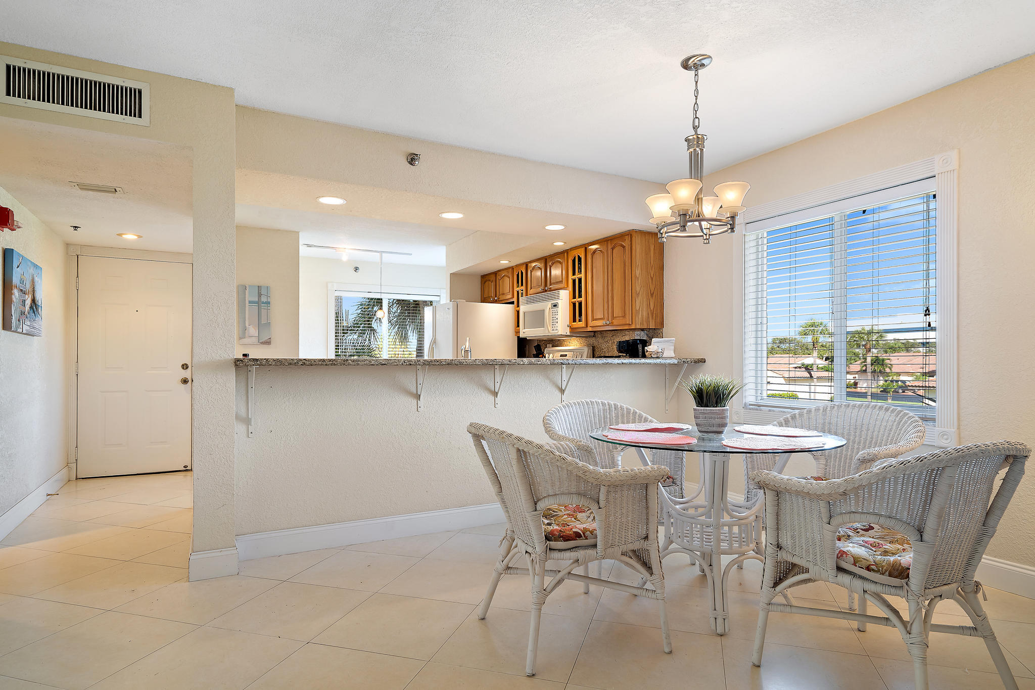 275 Palm Avenue, Unit C201 Jupiter, FL 33477 - Photo 11 of 24 a dining room filled a chandelier and kitchen view