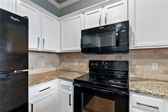 a kitchen with stainless steel appliances granite countertop white cabinets and black stove top oven with granite countertops