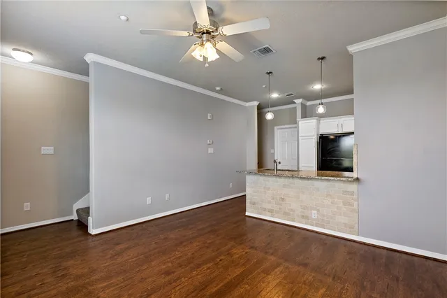 an empty room with wooden floor and a ceiling fan