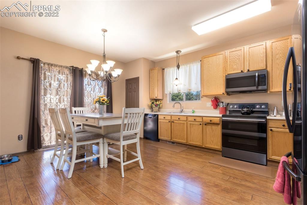 7542 Stephenville Road Peyton, CO 80831 - Photo 8 of 32 a kitchen that has a table chairs stainless steel appliances and wooden floor