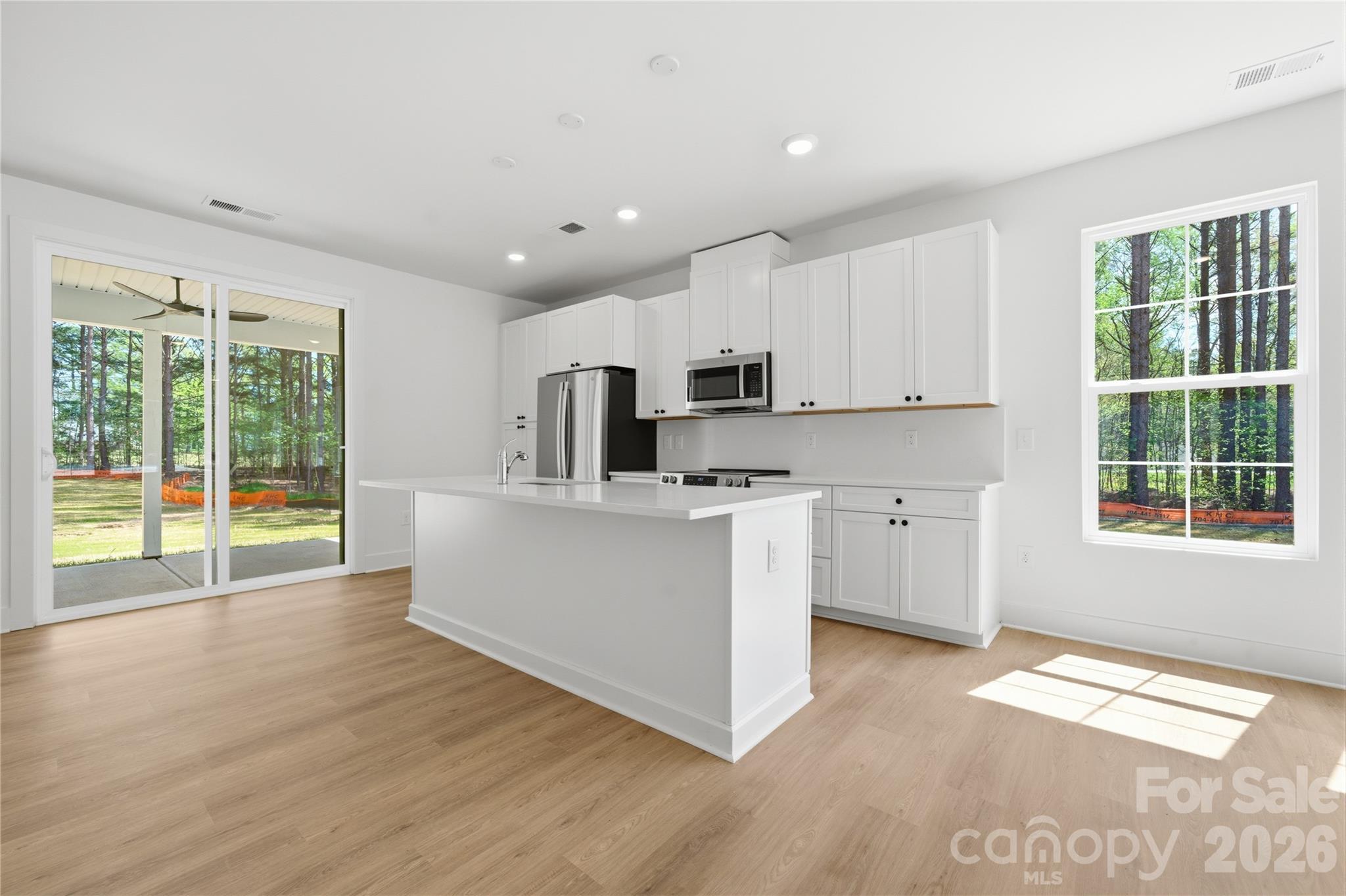 1412 Quiver Way York, SC 29745 - Photo 12 of 43 a large white open kitchen with stainless steel appliances granite countertop a stove a sink dishwasher and white cabinets with wooden floor