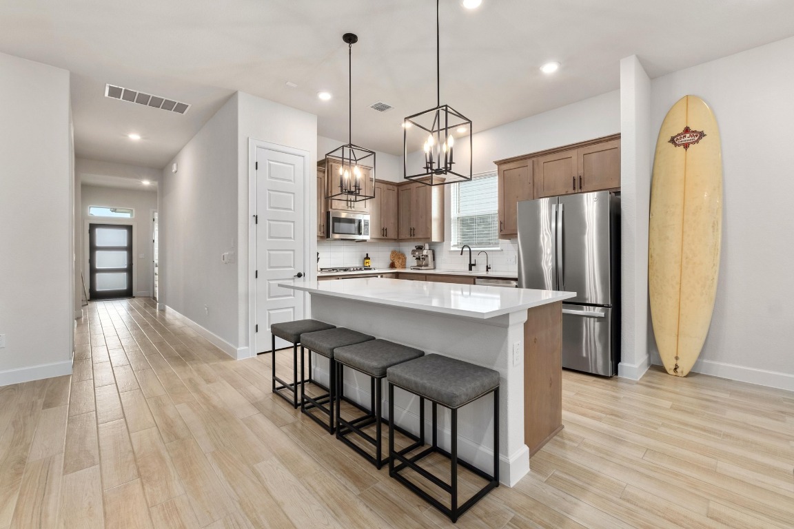 4513 Sea Salt Drive Austin, TX 78747 - Photo 7 of 31 a kitchen with stainless steel appliances a dining table chairs refrigerator and microwave