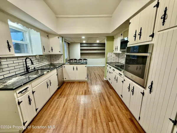 a large white kitchen with stainless steel appliances granite countertop a stove and a sink