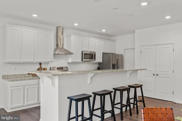 a kitchen with stainless steel appliances granite countertop a stove a sink a microwave a refrigerator and white cabinets