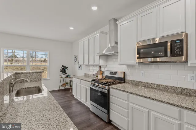 a kitchen with stainless steel appliances granite countertop a stove a sink and a microwave