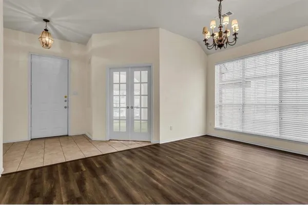 a view of an empty room with wooden floor and windows