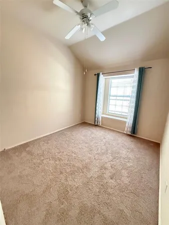 an empty room with a chandelier fan and windows