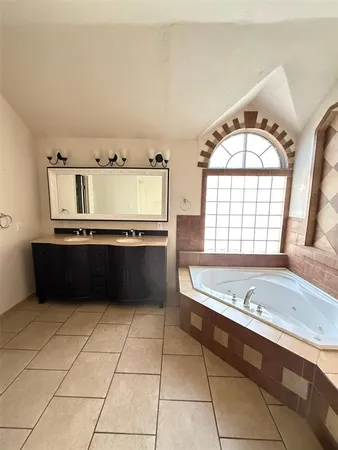 a spacious bathroom with a granite countertop bathtub a sink and a large window