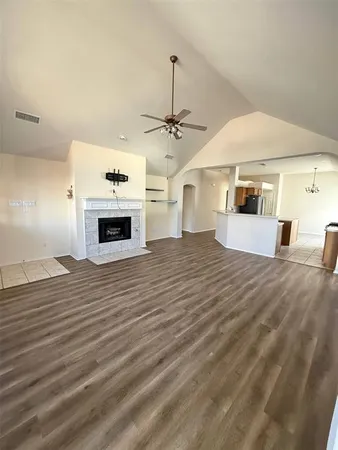 a view of a livingroom with a fireplace a chandelier and wooden floor