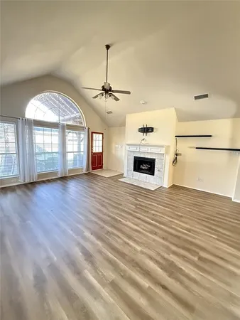 an empty room with wooden floor fireplace and windows
