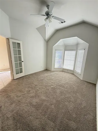an empty room with windows and ceiling fan
