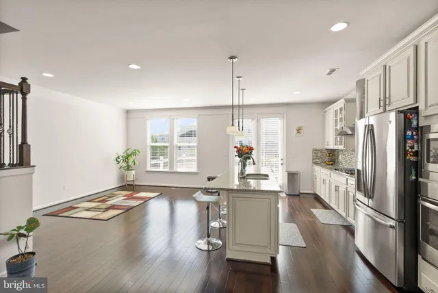 a kitchen with stainless steel appliances granite countertop a refrigerator a sink dishwasher a stove and white cabinets with wooden floor