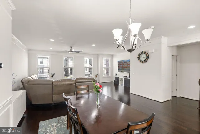a dining room with wooden floor a chandelier a wooden table and chairs