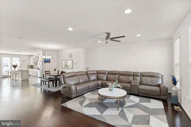 a living room with furniture and a dining table with wooden floor