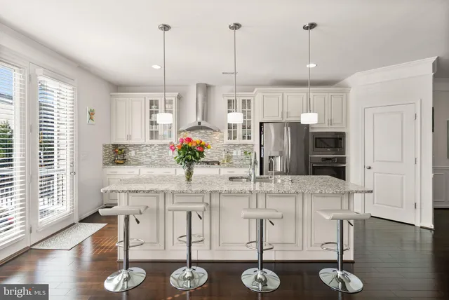 a kitchen with stainless steel appliances kitchen island granite countertop a table chairs and white cabinets