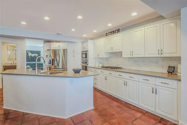 a large kitchen with granite countertop a sink and white cabinets