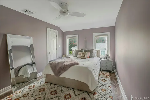 a bed sitting in a spacious bedroom next to a window and a mirror