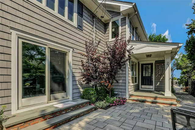 a view of a white house with a large windows and flower plants
