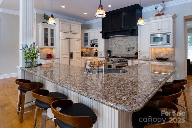 a kitchen with stainless steel appliances kitchen island granite countertop a table chairs in it and wooden floors