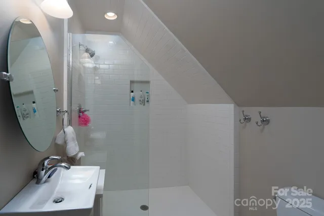 a bathroom with a sink and mirror with shower