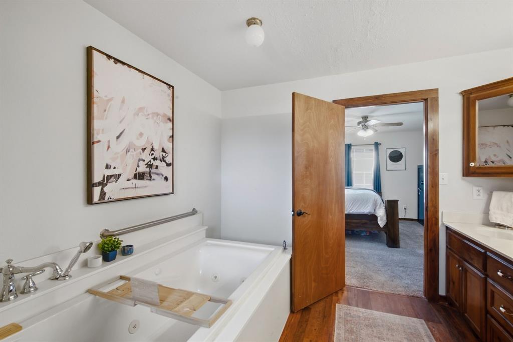 950 Johnson Bend Road Weatherford, TX 76088 - Photo 22 of 40 Built-in soaking tub with chrome fixtures, wood-finish flooring, and a vanity with a white countertop