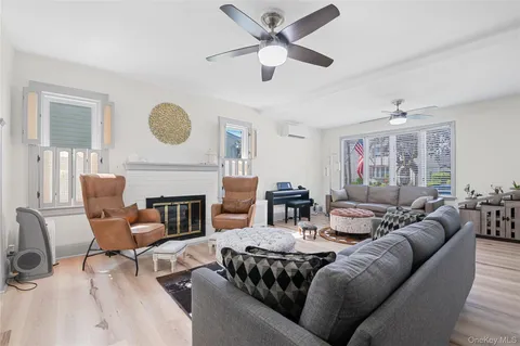 a living room with furniture a fireplace window and a ceiling fan