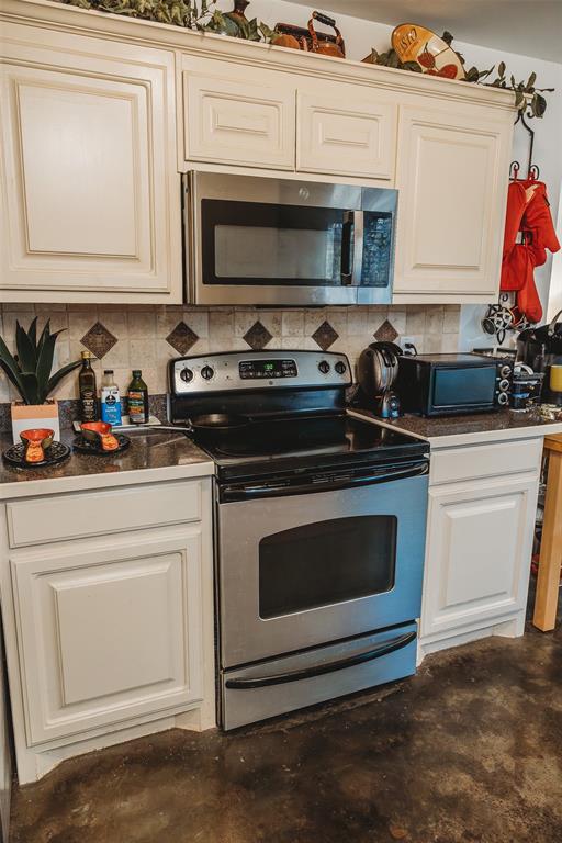6078 East Line Road Whitewright, TX 75491 - Photo 16 of 32 Kitchen with appliances with stainless steel finishes, dark countertops, concrete flooring, and decorative backsplash