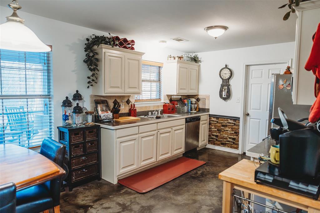 6078 East Line Road Whitewright, TX 75491 - Photo 17 of 32 Kitchen with finished concrete flooring, stainless steel dishwasher, hanging light fixtures, tasteful backsplash, and light countertops