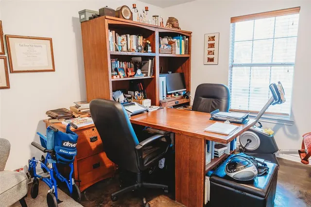a work room with furniture a rug and a window