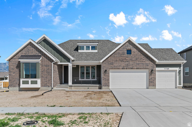View of front of house featuring a garage, driveway, covered porch, a shingled roof, and brick siding