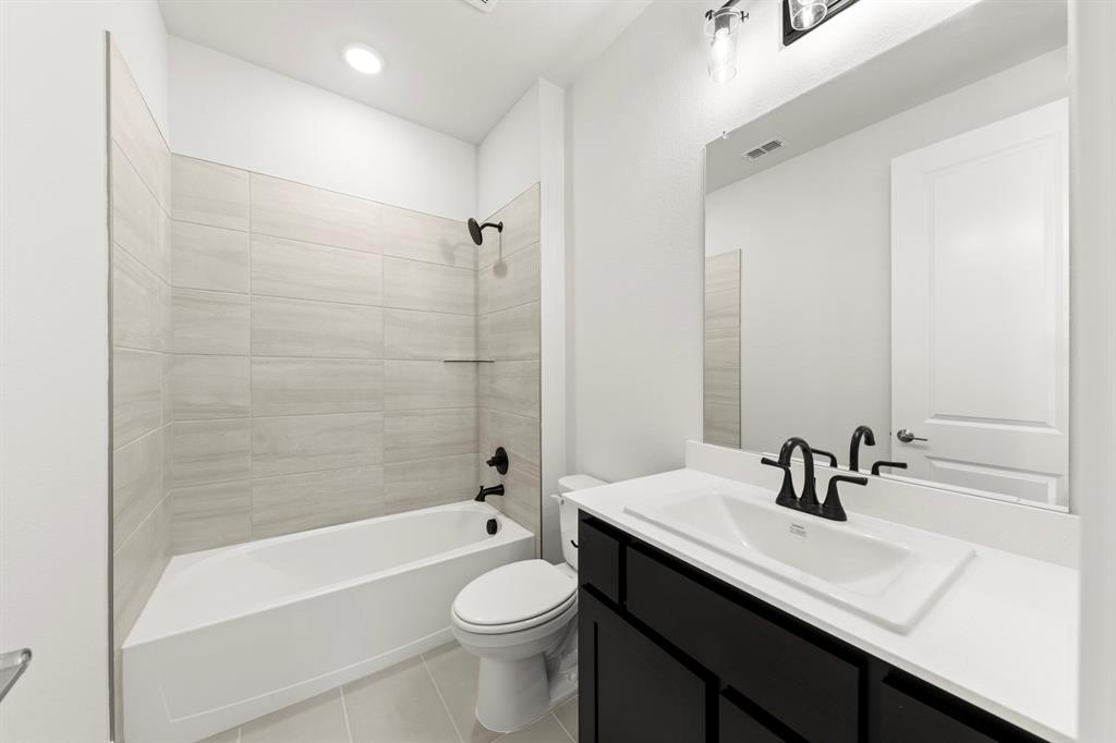 2917 Andesite Road McKinney, TX 75071 - Photo 12 of 27 a bathroom with a sink a toilet a mirror a bathtub and shower