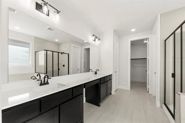 a bathroom with a double vanity sink a mirror and shower