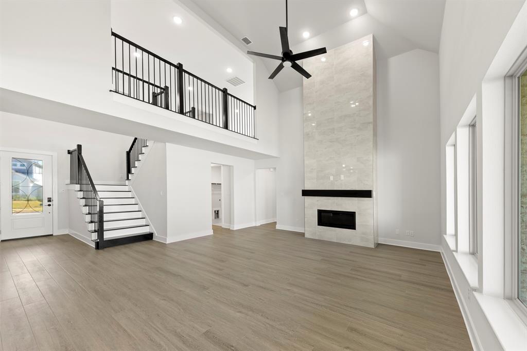 2917 Andesite Road McKinney, TX 75071 - Photo 5 of 27 an empty room with wooden floor fireplace and windows