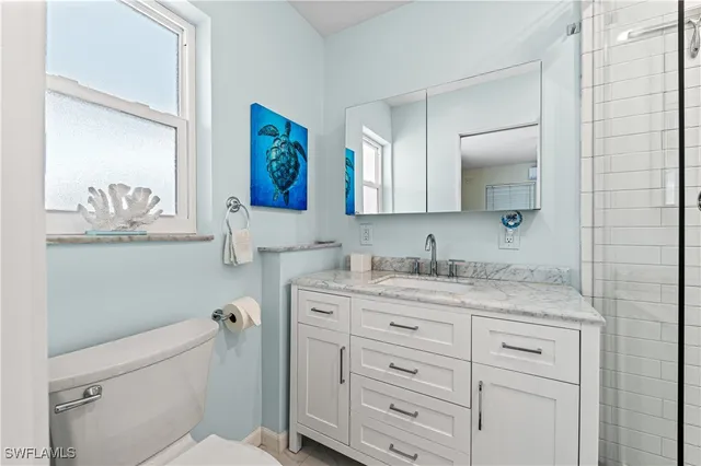 a bathroom with a granite countertop sink mirror vanity and toilet