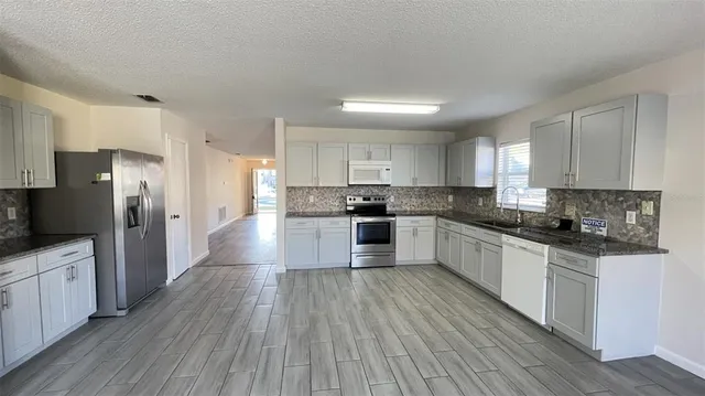 a large kitchen with cabinets wooden floor and stainless steel appliances