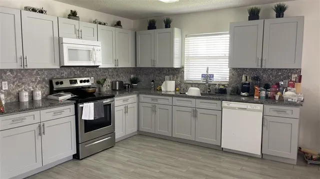 a kitchen with cabinets appliances a sink and a window