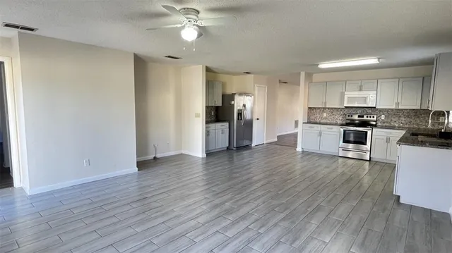 a view of a kitchen with a sink a refrigerator and wooden floor