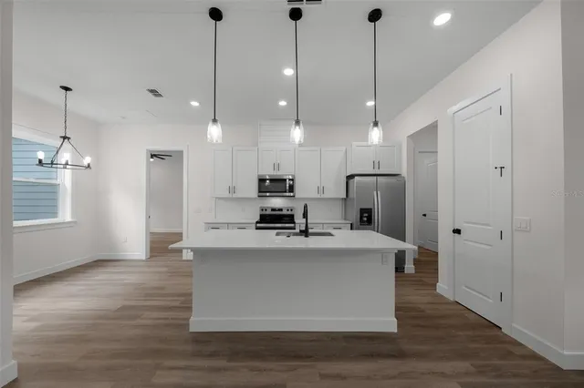 a view of kitchen with stainless steel appliances granite countertop cabinets and wooden floor