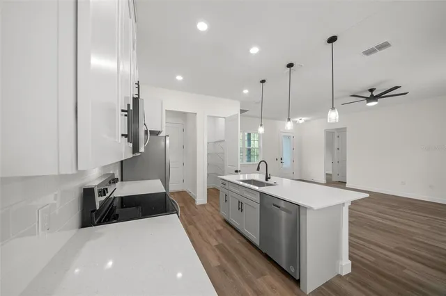 a large white kitchen with a large island oven a sink and stainless steel appliances
