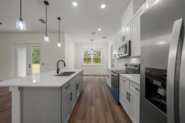 a large kitchen with stainless steel appliances granite countertop a sink a stove and a wooden floors