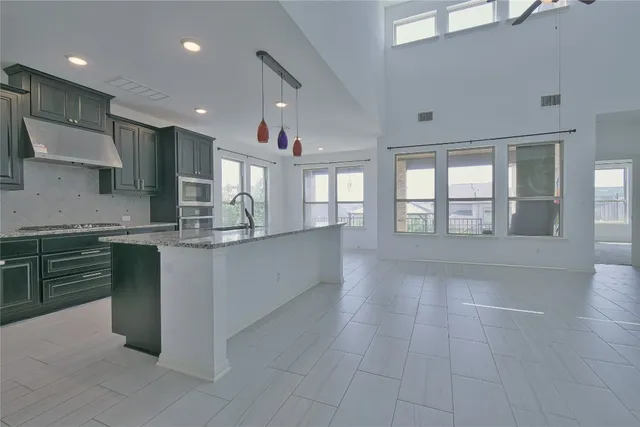an empty room with windows and chandelier fan