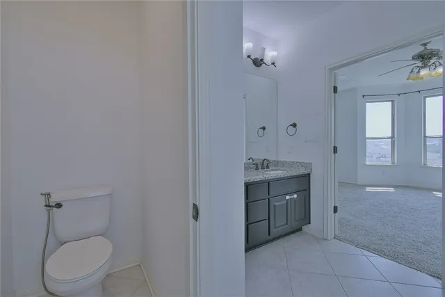 a bathroom with a granite countertop sink a toilet and a large mirror