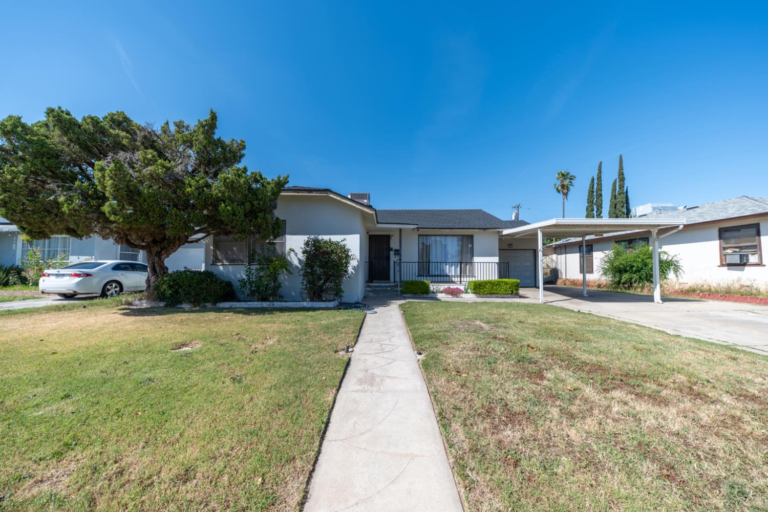 1004 West Pontiac Way Fresno, CA 93705 - Photo 3 of 34 a front view of a house with a yard and trees